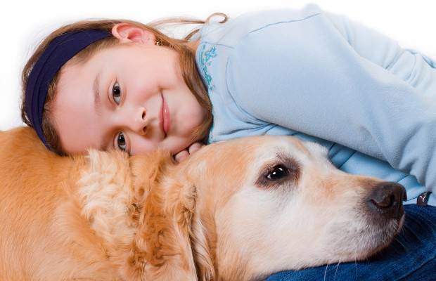 A young girl and golden retriever cuddle